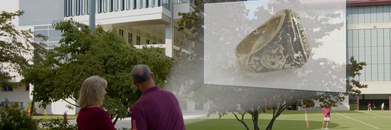 Two alumni looking at a projection of the Hokie class ring