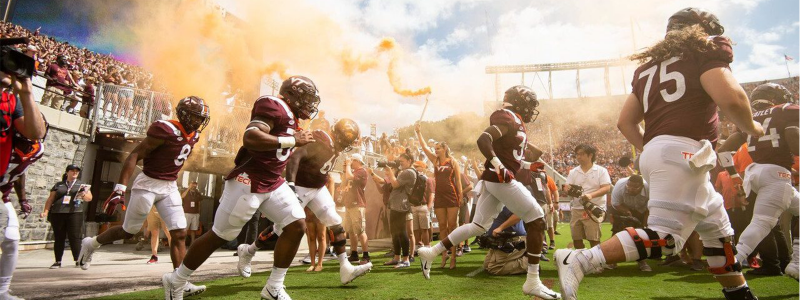 football players running onto the field in a cloud of orange smoke 