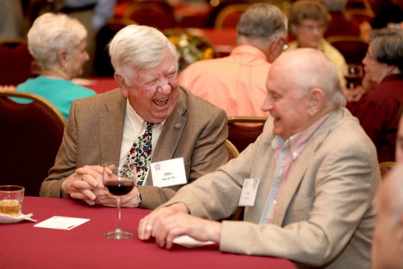 Two alumni laugh at a dinner at the Old Guard Reunion